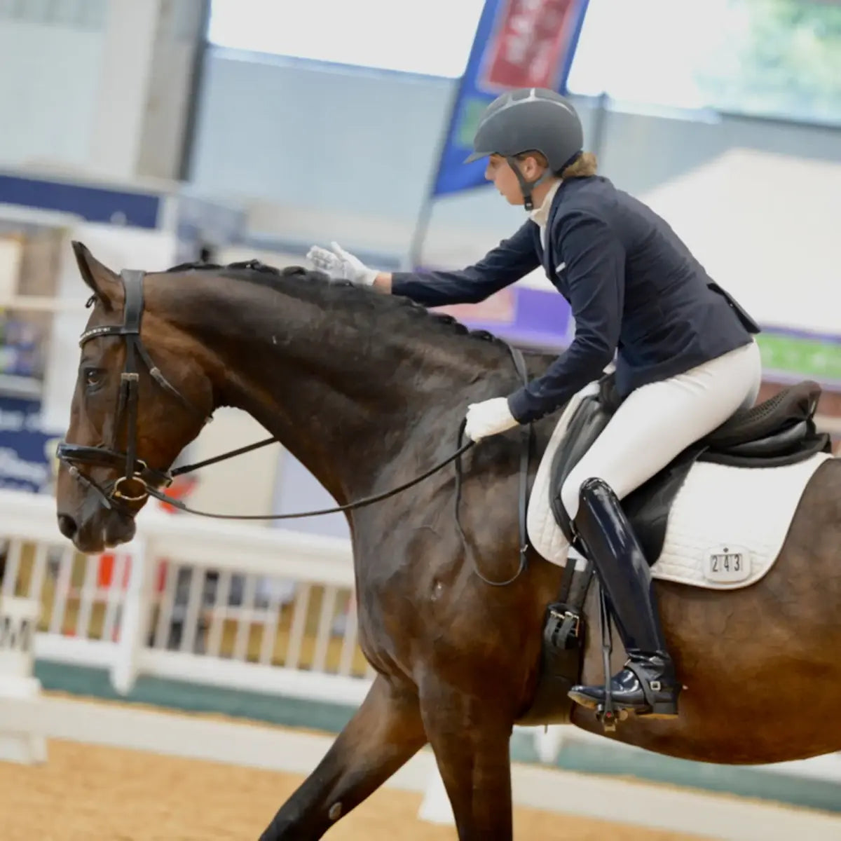 Person riding a horse in an indoor equestrian arena